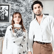 a man and a woman are standing next to each other in front of a painting of a horse