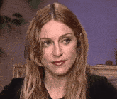 a close up of a woman 's face with long blonde hair and a black shirt .