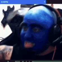 a man with blue paint on his face and headphones is making a funny face .