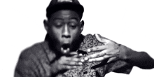 a black and white photo of a man wearing a hat and a shirt with his mouth open .