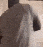 a man in a white shirt is standing in front of a white wall and holding a white shirt over his shoulder .