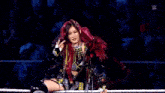 a woman with red hair is standing in a wrestling ring with a rope around her waist .