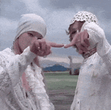 a couple of people standing next to each other and pointing at each other .