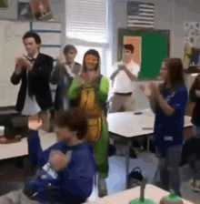 a group of people are standing in a classroom clapping .