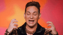 a man wearing a leopard print jacket and a gold chain around his neck is making a face