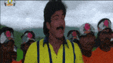 a man wearing a yellow shirt and suspenders is standing in front of a group of men wearing orange shirts