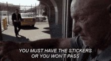 a man is looking out a window and says " you must have the stickers or you won t pass "