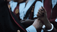 a woman with black nail polish is holding a man 's hand in handcuffs
