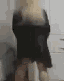 a blurry picture of a woman in a black dress standing in a room .