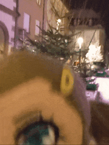 a close up of a person 's face with a blurred background and a christmas tree in the background