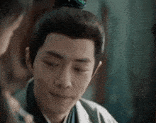 a man with a bun on his head is smiling and looking at another man .
