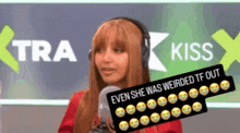 a woman wearing headphones stands in front of a sign that says " kiss "