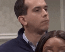 a man and a woman are standing next to each other and looking at something .
