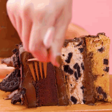a person is cutting a slice of cake with oreos on it
