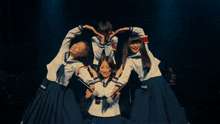 four girls in school uniforms are posing for a photo
