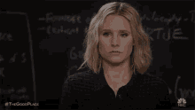 a woman is standing in front of a blackboard with a chalkboard behind her .