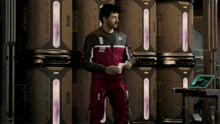 a man wearing a jacket with the number 01 on it stands in a room