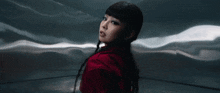 a woman in a red jacket is standing in front of a wall