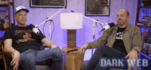 two men are sitting in front of microphones and a sign that says dark web on it