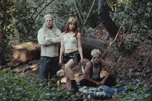 a group of people posing for a picture in the woods with a man laying on the ground