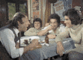a group of men are sitting at a table with a poster on the wall that says ' kadin ' on it