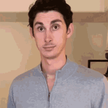a man in a grey sweater is making a face