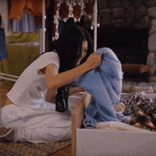 a woman in a white shirt is putting a blue blanket in a drawer that says ' i love you ' on it