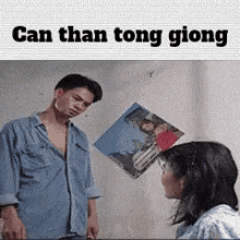 a man and a woman are standing next to each other in front of a picture on the wall .