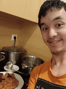 a man in an orange shirt is smiling in front of pots and plates of food