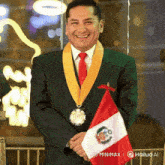 a man in a suit and tie is smiling while holding a small flag