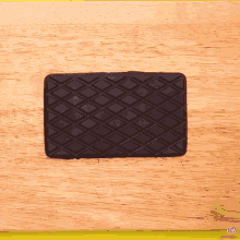 a piece of black rubber is sitting on a wooden board