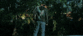 a man wearing a superman t-shirt and a hoodie is standing in a forest