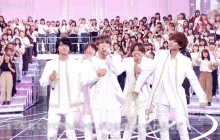a group of people are standing on a stage with a crowd behind them