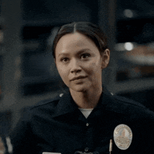 a woman in a police uniform is smiling and wearing a badge with the number 1 on it