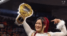 a woman in a white dress is holding up a wrestling championship belt