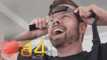 a man is wearing glasses and the number 84 is behind him