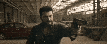 a man with a beard is holding a gun in a garage .