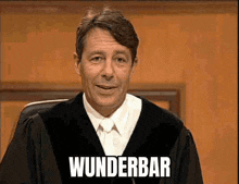 a man in a judge 's robe is smiling and the word wunderbar is on the screen