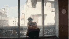 a man is sitting in front of a large window looking out