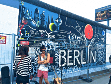 a man stands in front of a wall that says berlin on it