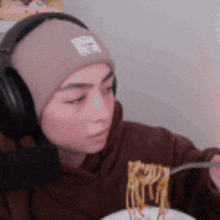 a woman wearing headphones is eating spaghetti with a fork .
