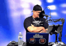 a man is sitting in front of a microphone with a dj racer laptop in front of him
