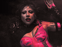 a woman in a pink and black outfit has a tattoo on her arm that says ' lady gaga ' on it