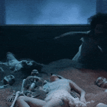a naked woman is laying on the ground with skeletons in the background