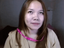 a close up of a woman wearing a pink lanyard around her neck .