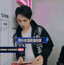 a man is holding a bunch of money in front of a sign that says 50 on it