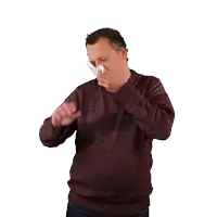 a man blowing his nose into a napkin while wearing a maroon sweater