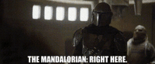 a man in a helmet is standing in a room and says `` the mandalorian : right here . ''