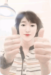a woman in a striped shirt giving a thumbs up sign