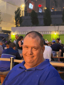 a man in a blue shirt smiles in front of a crowd of people